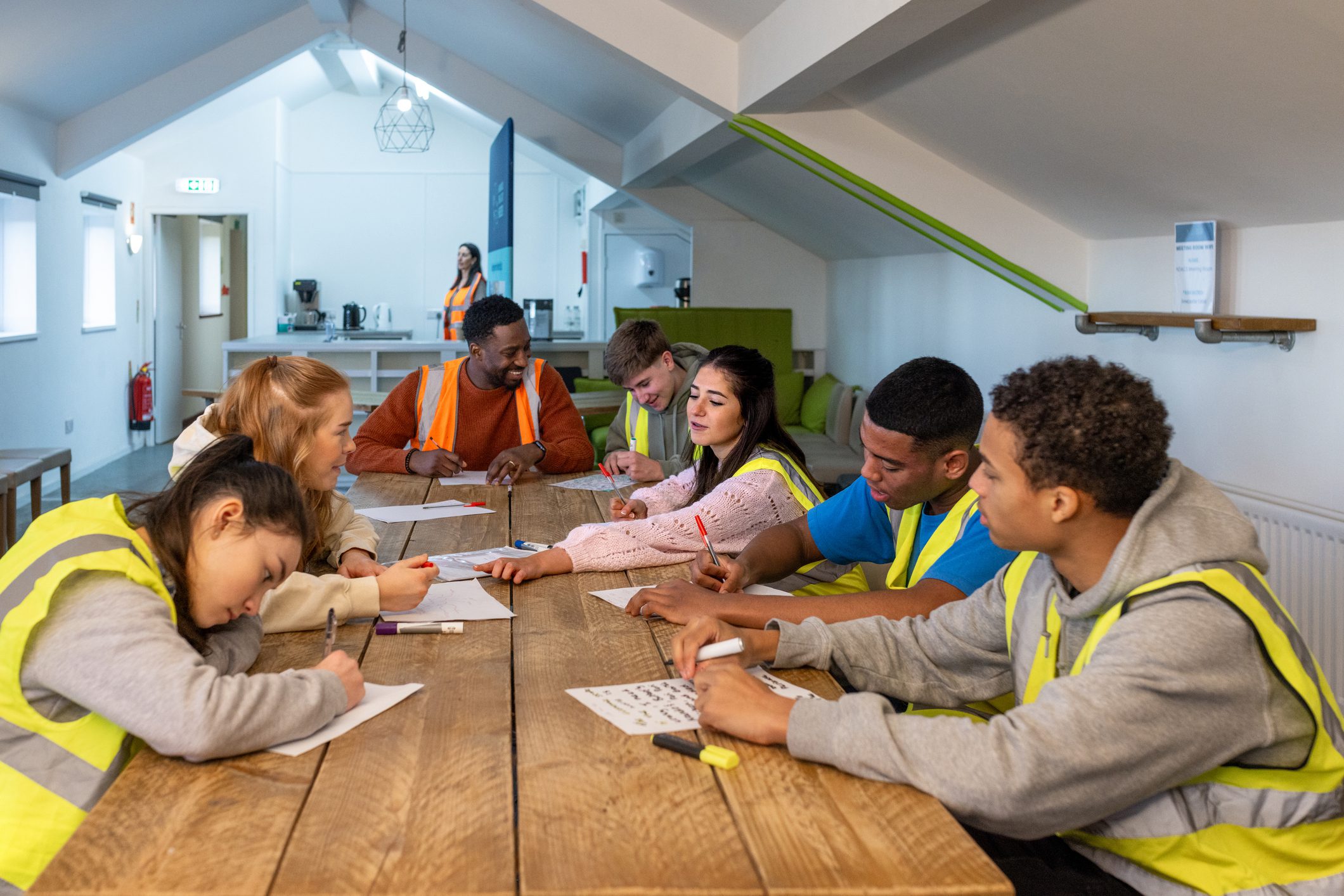 Children and adults enjoying creative activities at a large wooden table.